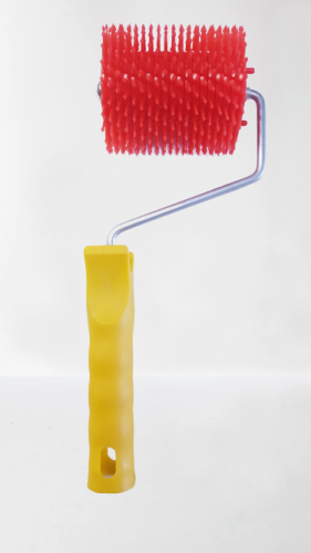 Plastikowy rozluźniacz do miodu, wałek z plastikową, żółtą rączką, wygiętym metalowym przedłużeniem oraz czerwonym, plastikowym wałkiem z igiełkami.