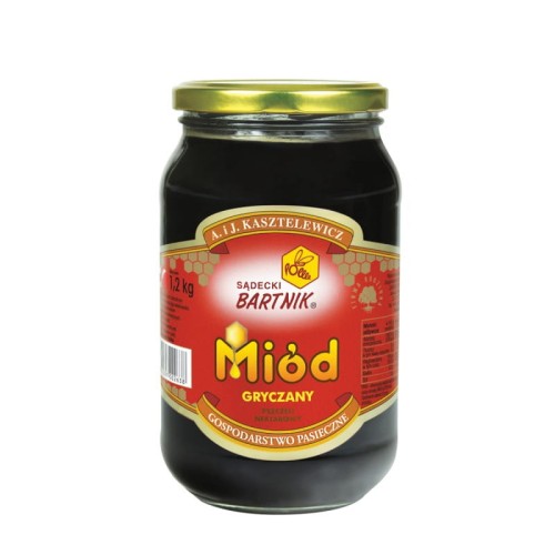 Miód gryczany 1,2 kg - Sądecki Bartnik. Przezroczysty słoik z ciemno brązową zawartością oraz złotą zakrętką. Etykieta jest w kolorze czerwonym. Etykieta zawiera logo, nazwę, producenta, pojemność oraz skład.