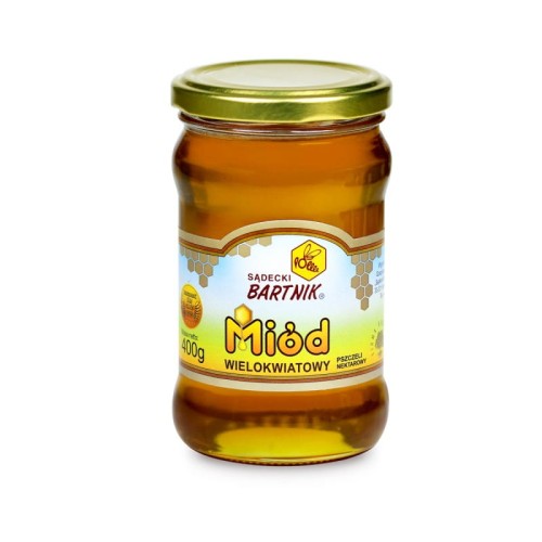 Miód wielokwiatowy 0,4 kg - Sądecki Bartnik. Przezroczysty słoik z żółtą zawartością oraz złotą zakrętką. Etykieta jest w kolorze niebieskim i zielonym, żółtym.  Etykieta zawiera logo, nazwę, producenta, pojemność oraz skład.