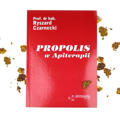 Zdjęcie przedstawia czerwoną książkę z tytułem "Propolis w Apiterapii" w kolorze białym oraz autorem "Prof. dr. hab. Ryszardem Czarneckim". Wokół książki są rozsypane grudki propolisu.