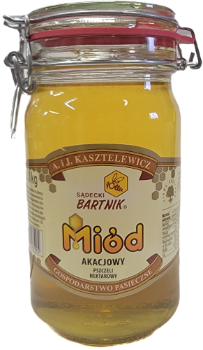 Miód Akacjowy Komfort - Sądecki Bartnik o pojemności 1 kg. Jasno żółty miód w przezroczystym słoik z pokrywką zamykaną na klamrę. Słoik posiada beżową etykietę , na której są podstawowe informacje: nazwa, producent, waga, kraj.