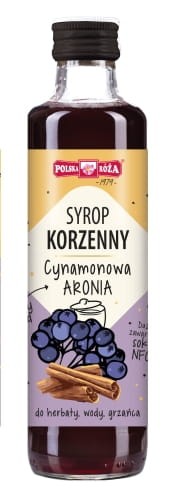 Szklana butelka z syropem cynamonowa aronia. Etykieta jest beżowo-fioletowa, na której jest grafika jeżyn i cynamonu, a także niezbędne informacje o pojemności, kraju pochodzenia, składzie. Pojemność 250 ml.