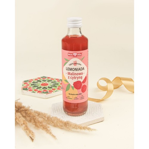 Lemoniadę malinową z cytryną w butelce z różową etykietą i owocami maliny oraz cytryny. Butelka wpisana jest w kompozycję na różowym tle. Pojemność 250 ml.